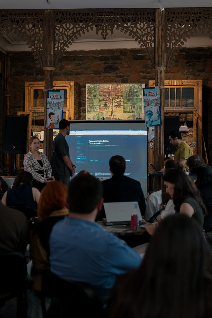 Themis Labs presenting their new AI prototypes to an audience, with a large presentation screen displaying digital safety concepts.